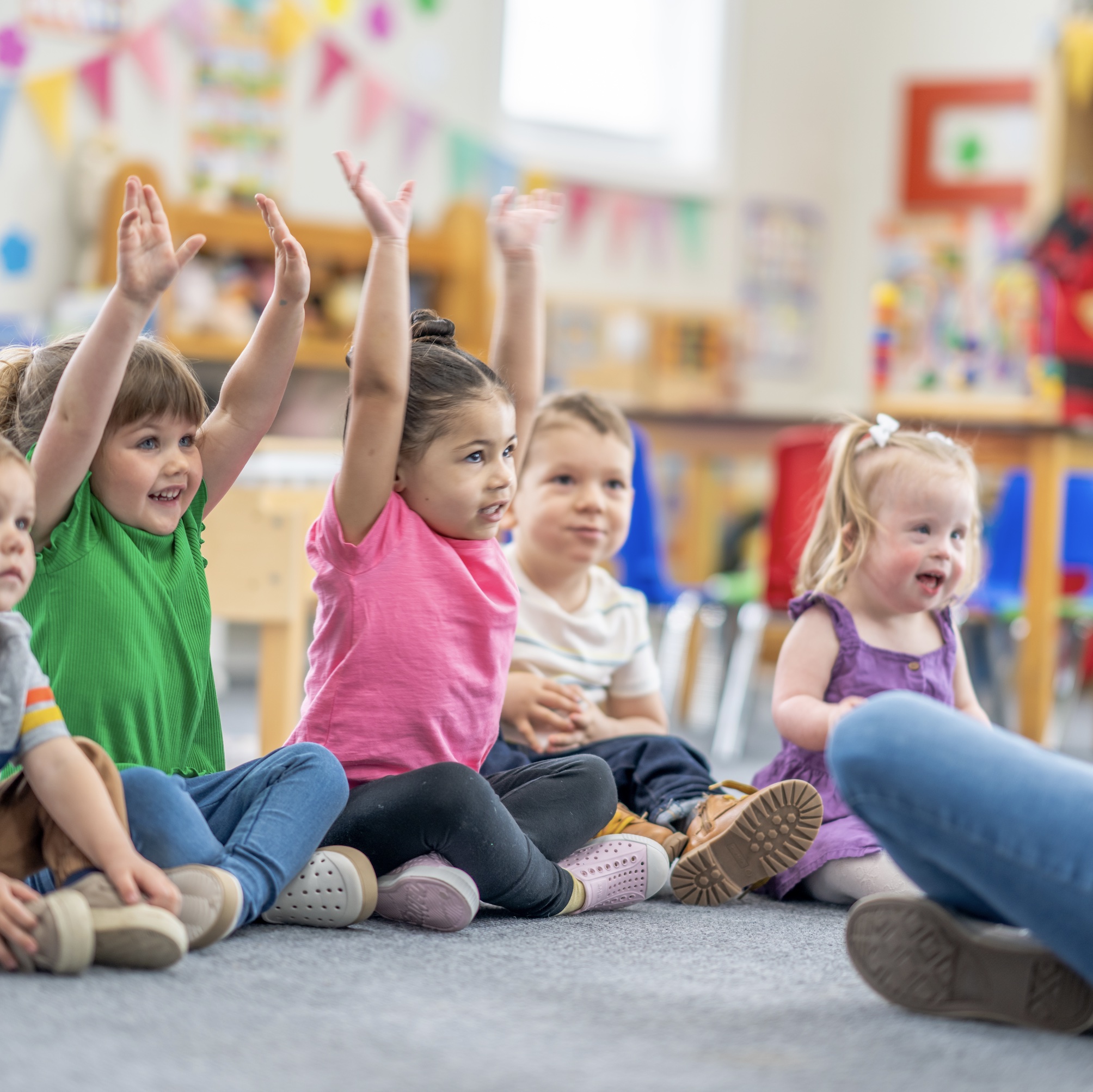 a group of preschoolers raising their hands to answer a question